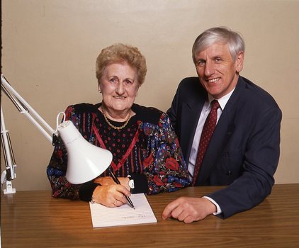 John Cook sitting next to a woman writing on a thickly lined notepad