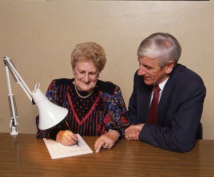 John Cook sitting next to a woman writing on a thickly lined notepad