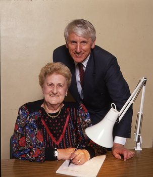 John Cook sitting next to a woman writing on a thickly lined notepad