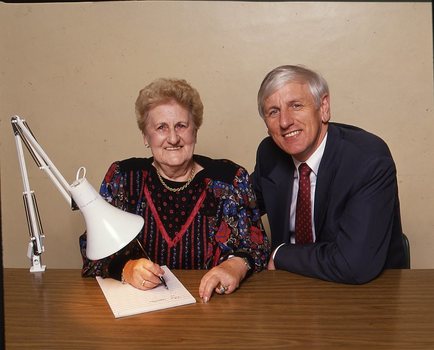 John Cook sitting next to a woman writing on a thickly lined notepad