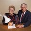 John Cook sitting next to a woman writing on a thickly lined notepad