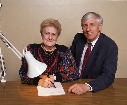 John Cook sitting next to a woman writing on a thickly lined notepad