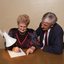 John Cook sitting next to a woman writing on a thickly lined notepad