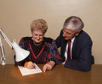 John Cook sitting next to a woman writing on a thickly lined notepad