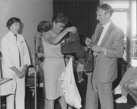 B/W photograph of John Cook presenting boots to a staff member