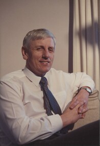 White shirt with gray tie with arm resting on couch
