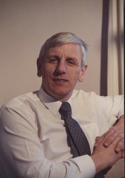 White shirt with gray tie with arm resting on couch