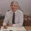 Sitting at his desk with piles of documents in the background
