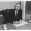 John Cook sitting at his desk with pen in hand