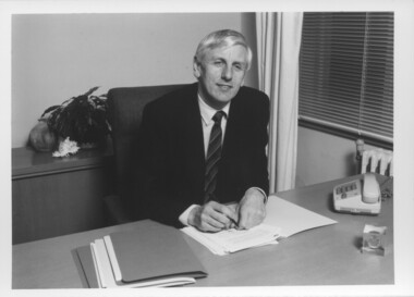 John Cook sitting at his desk with pen in hand
