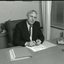 John Cook sitting at his desk with pen in hand