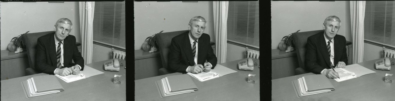 John Cook sitting at his desk with pen in hand