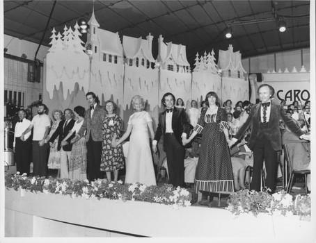 Line of performers hold hands as the stand on the stage at rehearsal