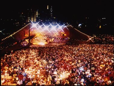 Melbourne city skyline at night with Myer Music Bowl and crowds