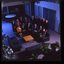 15 people sit around a small table and turn towards the photographer who is a floor above them