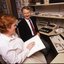 Robin Pleydell sits next to AFB Staff member at her workstation whilst she is reading Braille