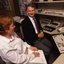 Robin Pleydell sits next to AFB Staff member at her workstation whilst she is reading Braille