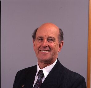 Man in dark blue suit, white shirt, multi-coloured tie