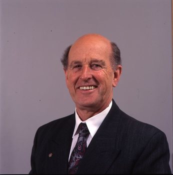 Man in dark blue suit, white shirt, multi-coloured tie