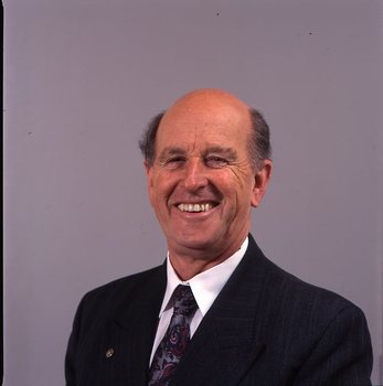 Man in dark blue suit, white shirt, multi-coloured tie