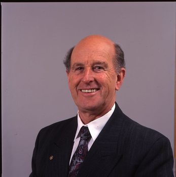 Man in dark blue suit, white shirt, multi-coloured tie