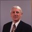 John Cook in dark suit with white shirt and red and gold tie