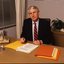 John Cook sitting at his desk with pen in hand