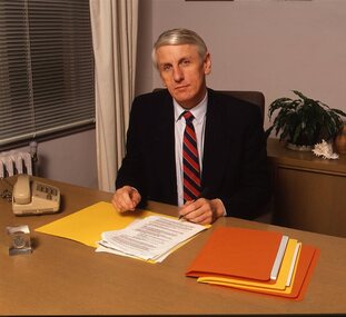 John Cook sitting at his desk with pen in hand