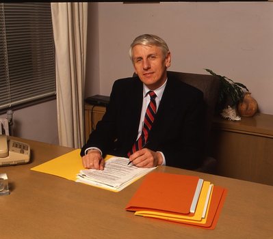 John Cook sitting at his desk with pen in hand