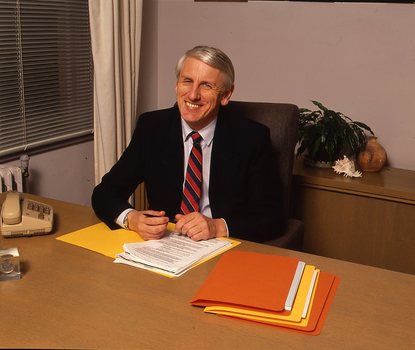 John Cook sitting at his desk with pen in hand