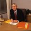 John Cook sitting at his desk with pen in hand