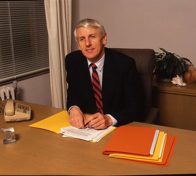 John Cook sitting at his desk with pen in hand