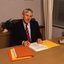 John Cook sitting at his desk with pen in hand