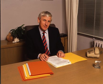 John Cook sitting at his desk with pen in hand