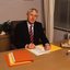 John Cook sitting at his desk with pen in hand