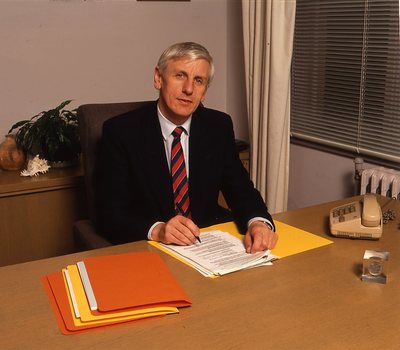 John Cook sitting at his desk with pen in hand