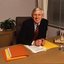 John Cook sitting at his desk with pen in hand