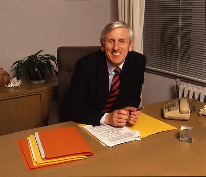 John Cook sitting at his desk with pen in hand