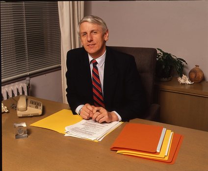 John Cook sitting at his desk with pen in hand