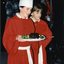 A chorister wearing a chef's hat holds a plate with a Christmas pudding accompanied by another chorister