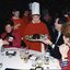 Chorister hands a Christmas pudding to a man with Carol O'Reilly on the left