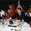 Carol O'Reilly claps as man puts Christmas pudding on table and chorister is about to place chef's hat on man's head