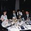 Three people around the table look at the menu, whilst two others pour wine or glance across the room