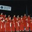 National Boys Choir dressed in red, with their conductor, in front of a starry backdrop and RVIB sign