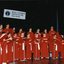 National Boys Choir dressed in red, with their conductor, in front of a starry backdrop and RVIB sign