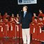 National Boys Choir dressed in red, with their conductor, in front of a starry backdrop with Peter Cupples