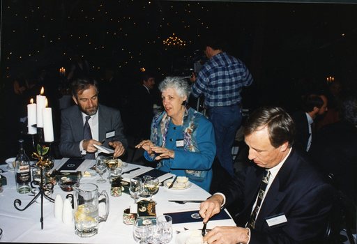 Two men and one woman seated at a table preparing for the lunch