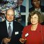 Male and female guest stand in front of a wall of Channel 9 celebrity portraits