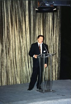 Pete Smith at a podium in front of a gold curtain