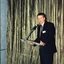 Acting CEO Len Evans gives a welcome address in front of a gold curtain